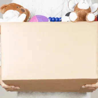 woman holding a cardboard box of children's stuffed animals and toys