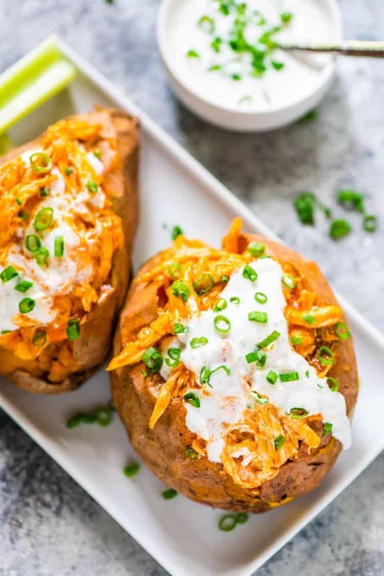 Healthy Slow Cooker Buffalo Chicken Sweet Potatoes with sauce and green onions