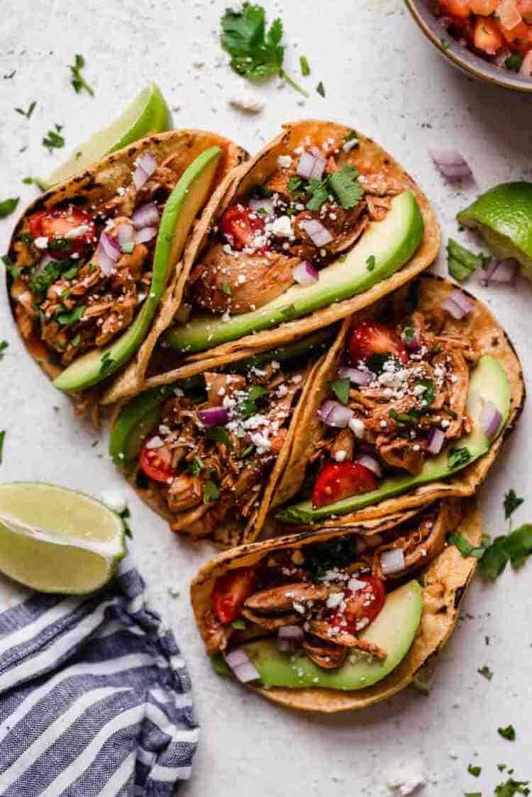 Slow Cooker Chicken Tacos with avocado red onions cherry tomatoes and parsley