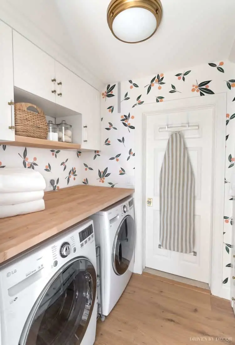 ikea laundry room organization ideas with cabinets above washer dryer under a wooden counter top and an iron hanging on the door