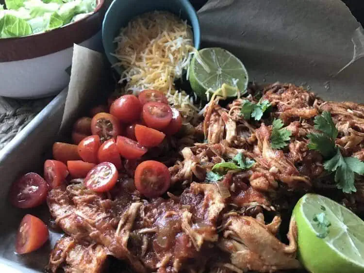 slow cooker chicken shredded mexican style with cherry tomatoes, lime, shredded cheese