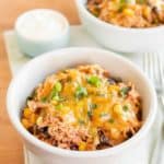 Slow Cooker Chicken Burrito Bowls with cheese and greens close up on a table