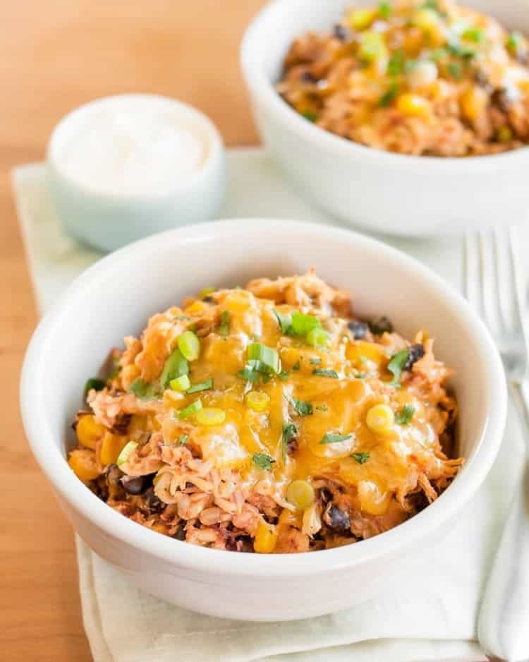 Slow Cooker Chicken Burrito Bowls with cheese and greens close up on a table