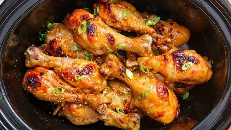 Crock-Pot Asian Chicken Drumsticks sprinkled with sesame seeds and green onions close photo