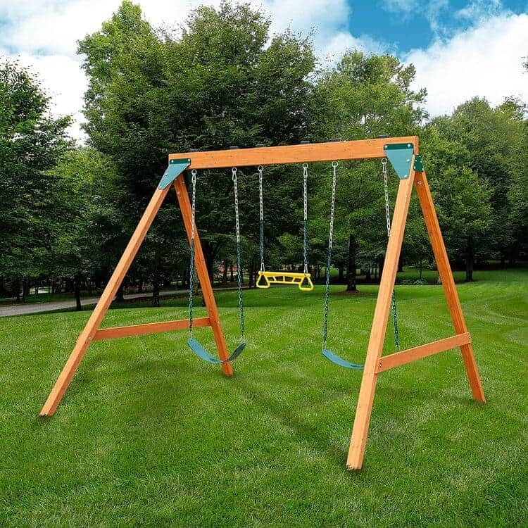 Wooden swing set with two swing seats, a ring and trapeze combination swing, all with metal pinch free coated chains, brow, green and yelow color, on a green landscape