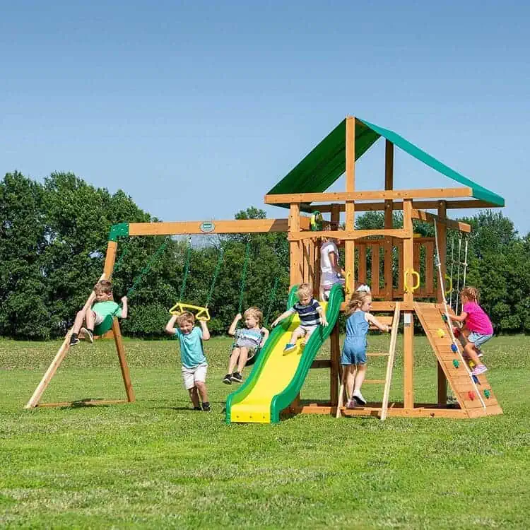 Wooden playset with double rock wall and a rope, swing beam with heavy duty steel brackets, wave slide and upper fort, brown and green on a green landscape