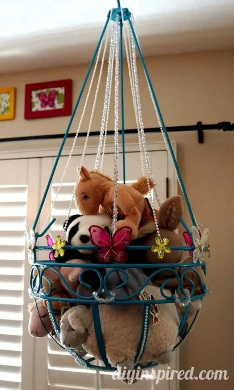 stuffed animal toy storage from a repurposed planter painted blue decorated with pearls and butterflies
