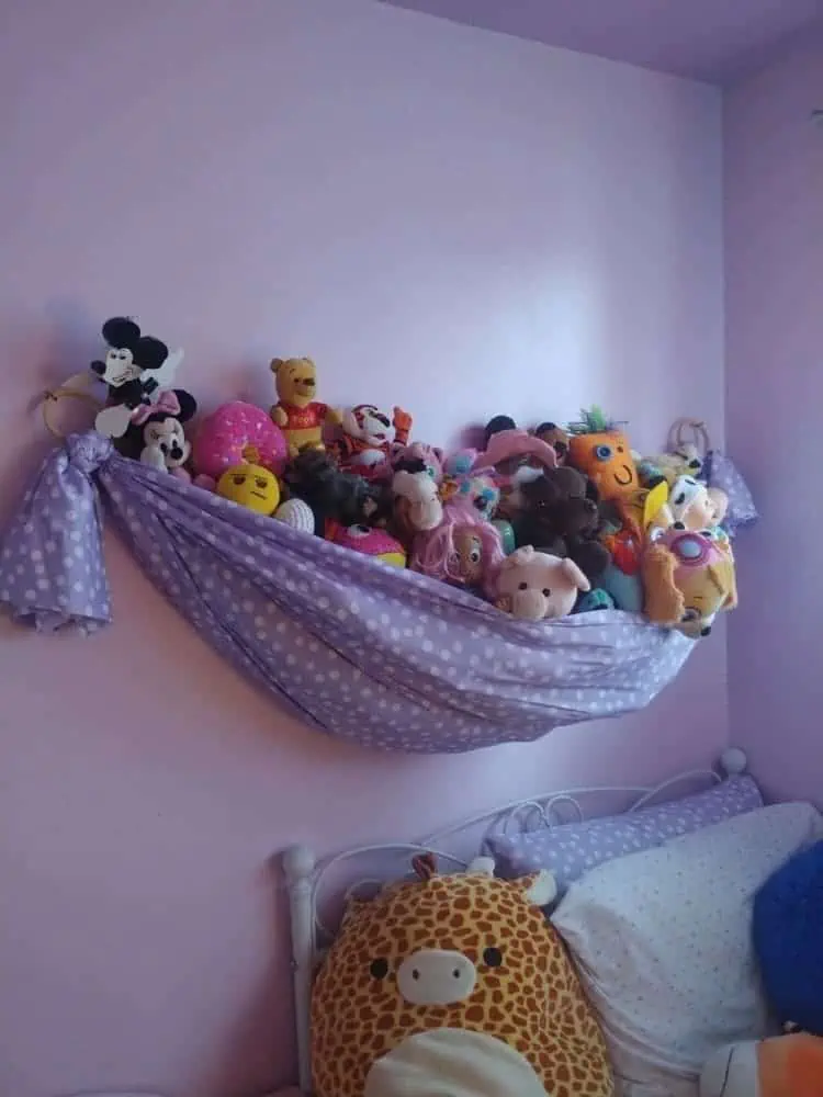 stuffed animal storage hammock hanged in a girls room over the bed to store all of the toys