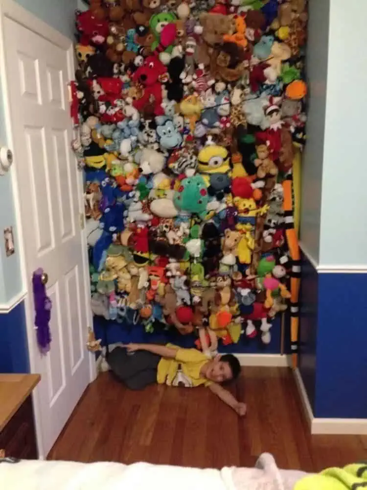 cargo net stuffed animal storage storage ideas a wall full of toys and a boy laying in front