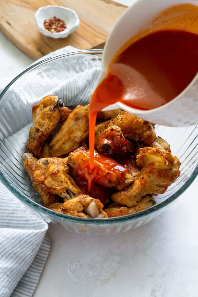 air fryer buffalo wings poured with red hot sauce