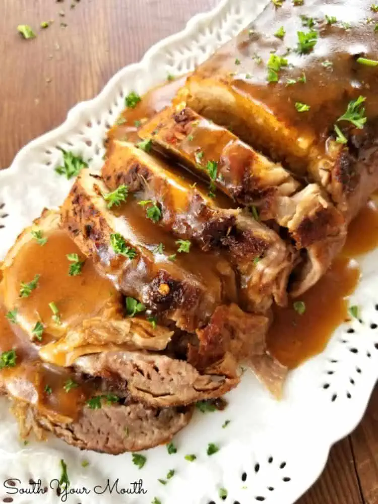 Butter-Braised Slow Cooker Pork Roast served on a white tray sprinkled with greens