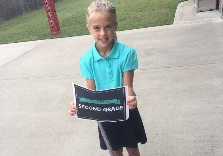 a girl holding a Printable Sign for Back to School second grade