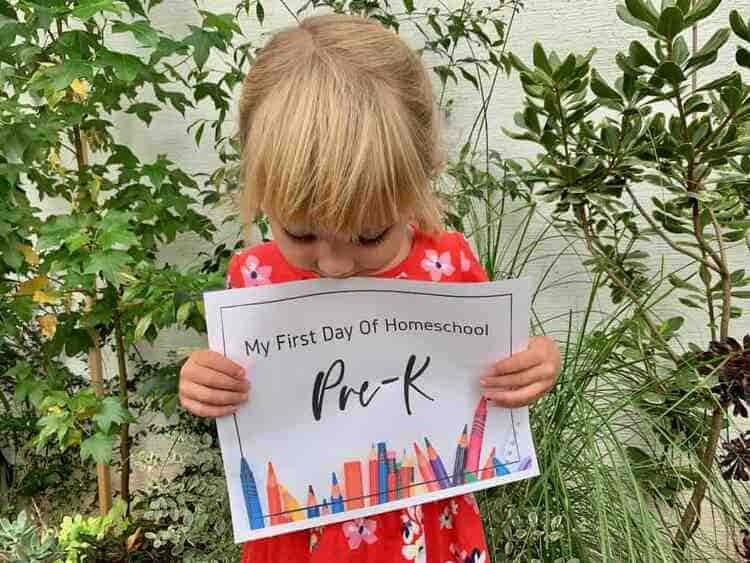 a little blonde girl holding a First Day of Homeschool Pre-k Printable for All Grades