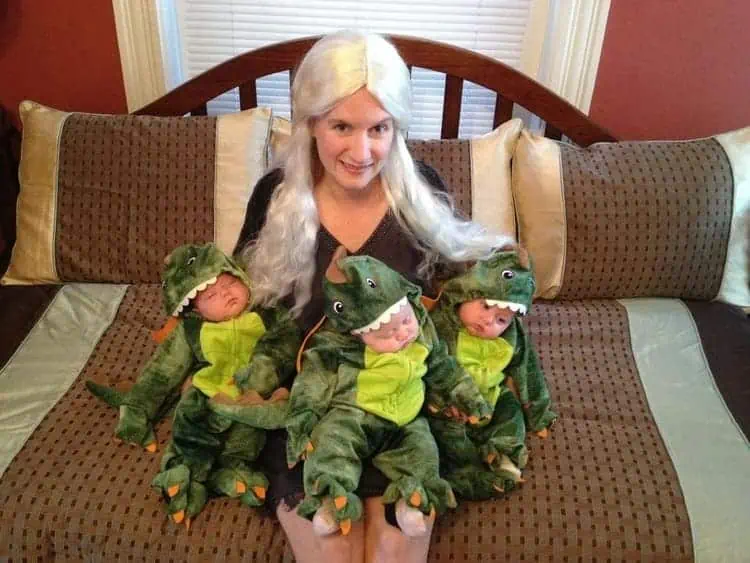 A Mother of Dragons with Triplets Halloween Costumes sitting on a bed holding the kids