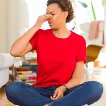 woman sitting on floor holding nose closed