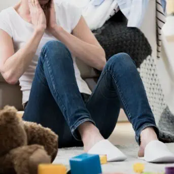 woman sitting on floor surrounded by toys