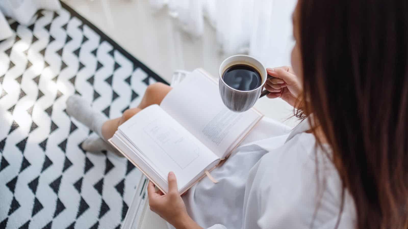 woman drinking coffee and reading a book