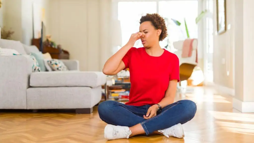 woman sitting on floor holding nose closed