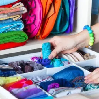 womans hands reaching into drawer of clothing separated by drawer dividers