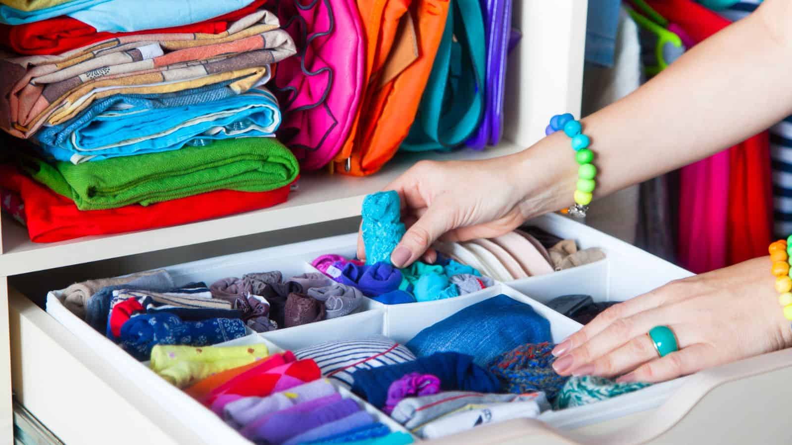 Neatly folded clothes with accessories in chest of drawers