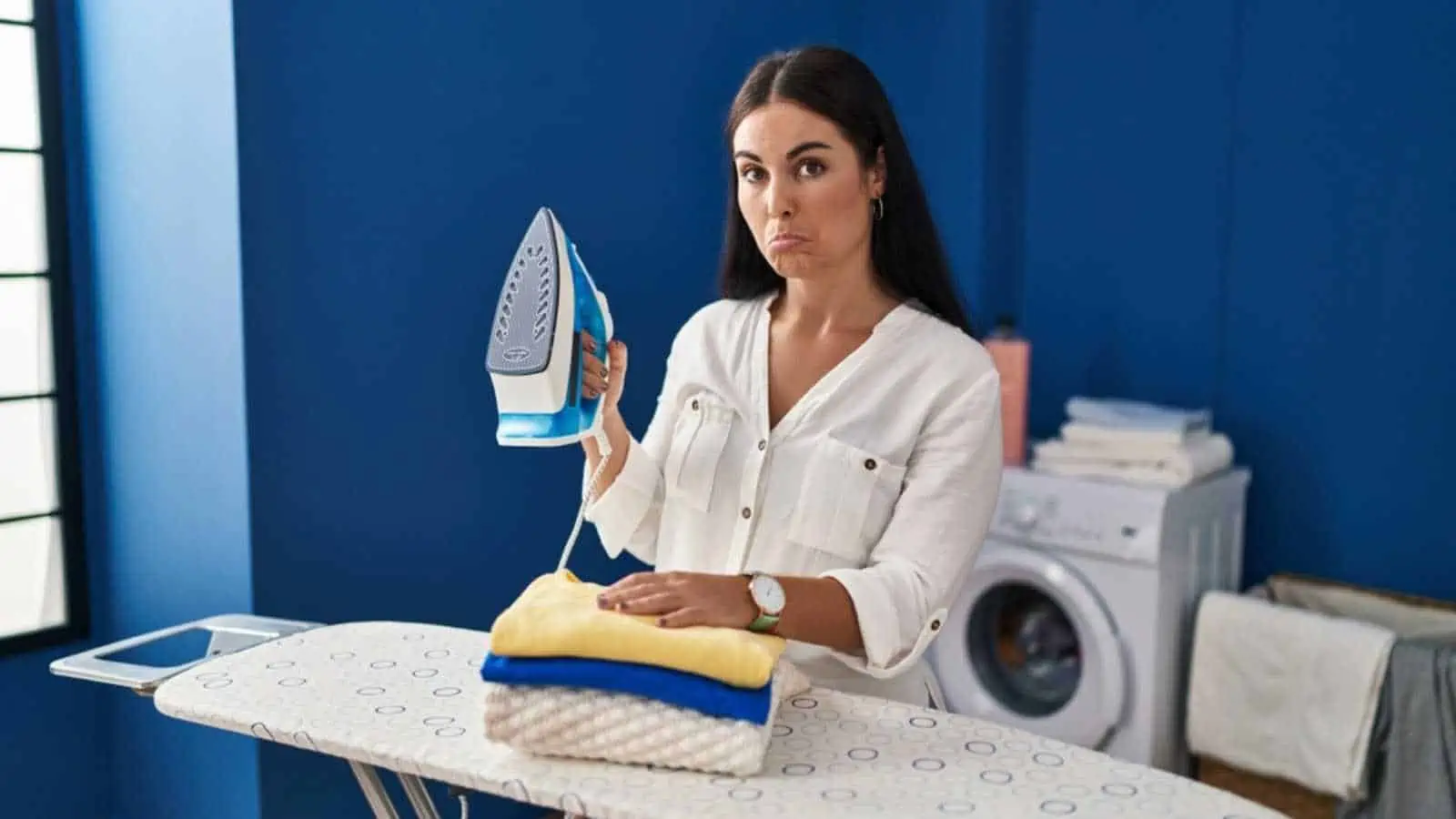 Young hispanic woman with folded laundry after ironing depressed and worry for distress, crying angry and afraid. sad expression.