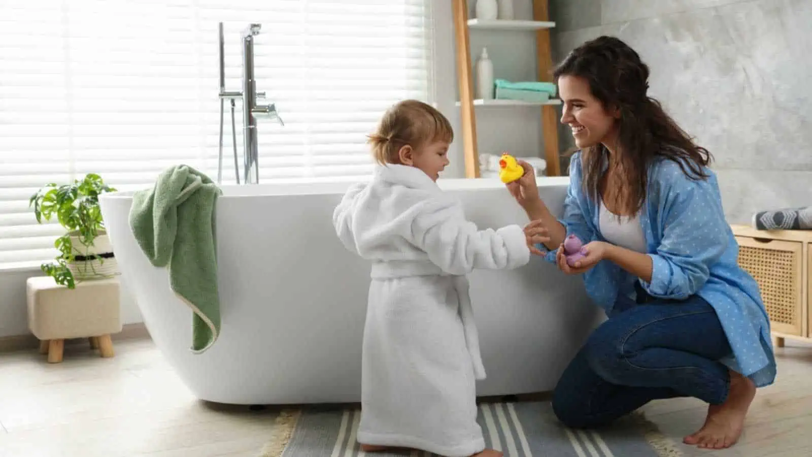 Mother playing with her daughter near tub in bathroom