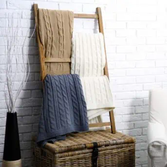 beige gray and white blankets on blanket ladder next to white chair