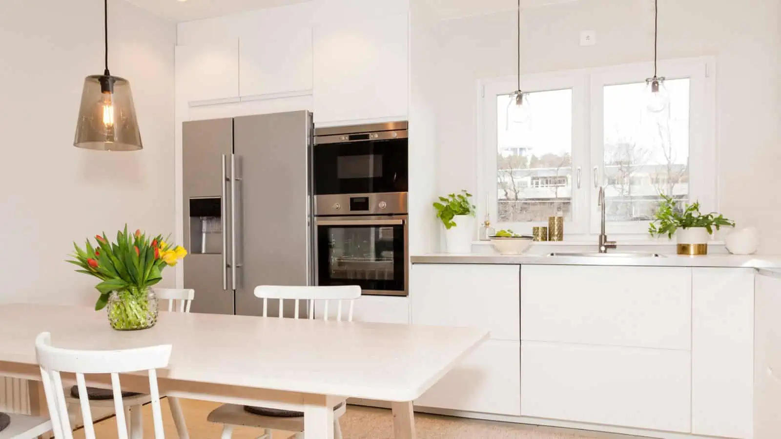 clean white kitchen and stainless steel fridge and ovens