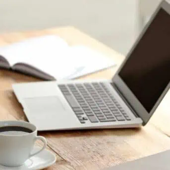 laptop on table with phone coffee and books