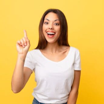 happy woman pointing up yellow background