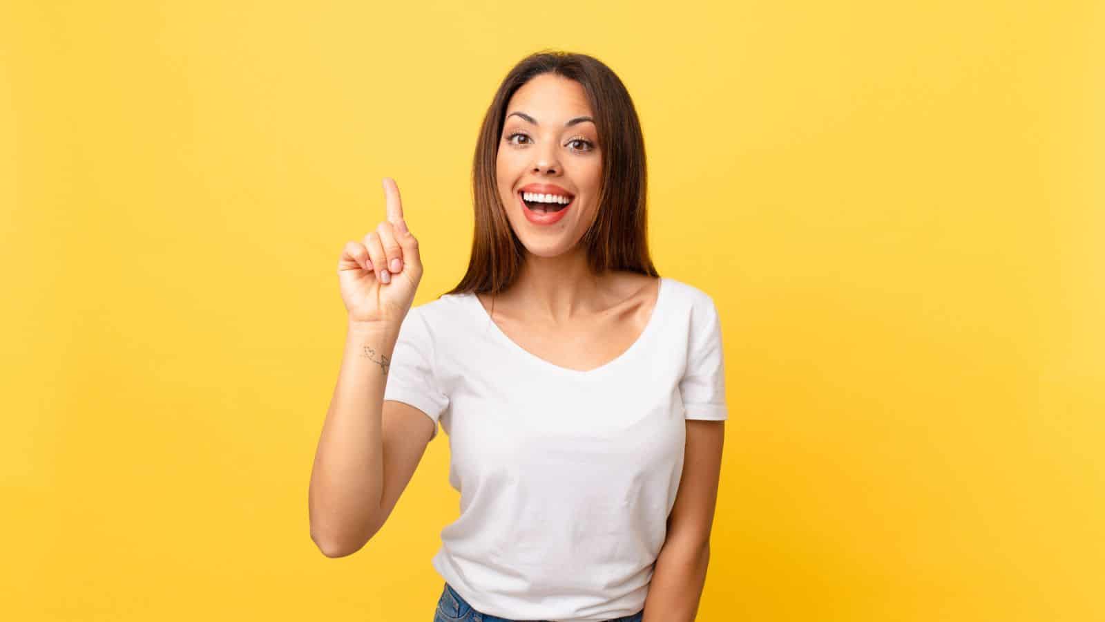 happy woman pointing up yellow background