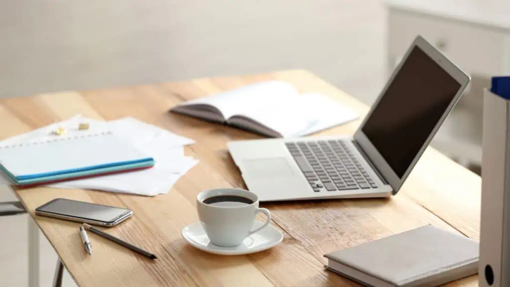 laptop on table with phone coffee and books