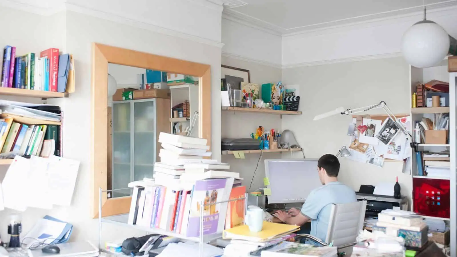 man working at computer in cluttered office