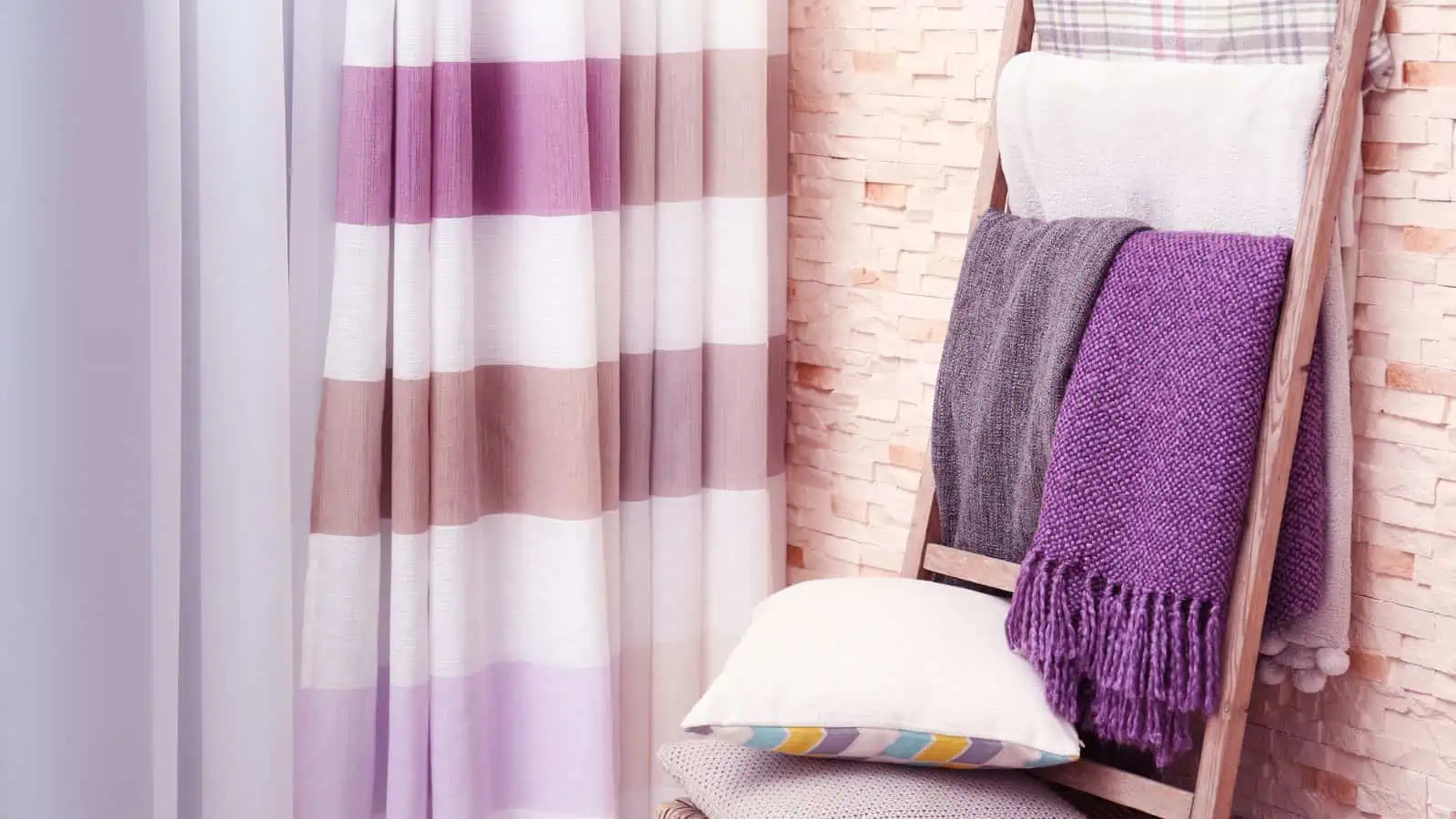 purple cream and gray blankets on blanket ladder next to matching curtain