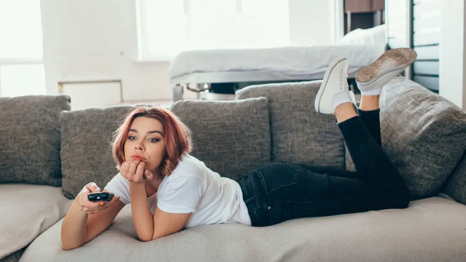 woman lying on couch holding remote