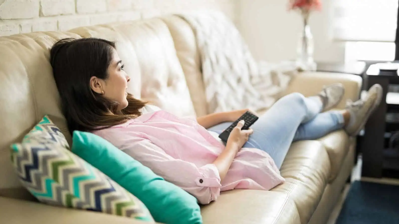 woman relaxing on couch holding remote control