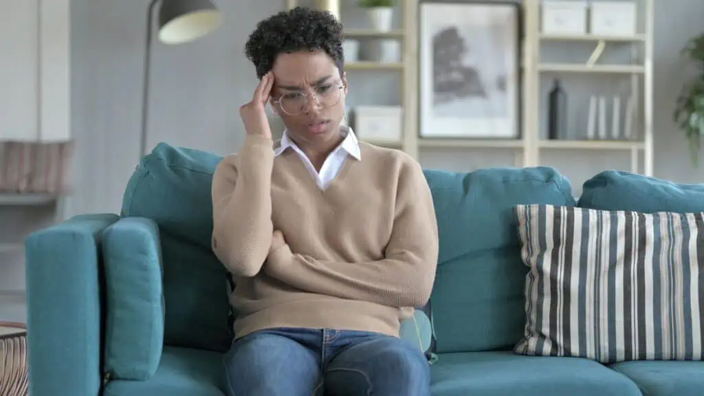 woman sitting on a couch with fingers to her temple