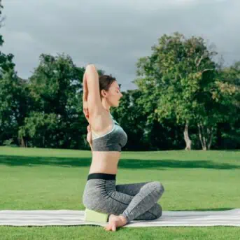 woman sitting on yoga mat and block outside