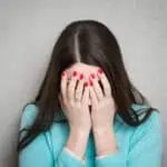 Woman covering her face with both hands isolated