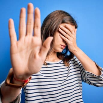 Young beautiful blonde girl wearing casual sweater standing over blue isolated background covering eyes with hands and doing stop gesture with sad and fear expression. Embarrassed and negative concept.