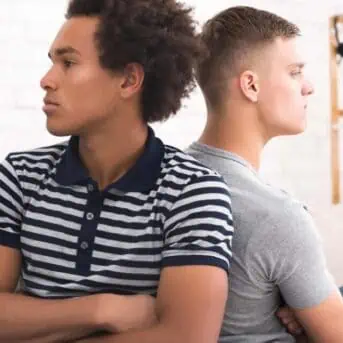 Men's quarrel. Two angry roommates sitting back to each other at home