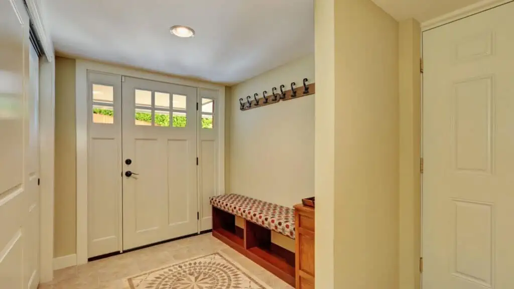 entryway of home with door rug and bench with wall hooks above
