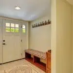 entryway of home with door rug and bench with wall hooks above