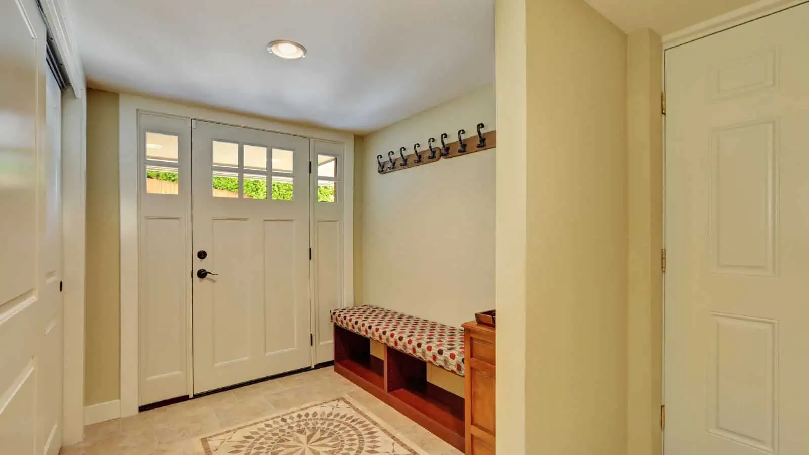entryway of home with door rug and bench with wall hooks above