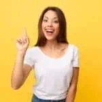 happy woman pointing up yellow background (1)