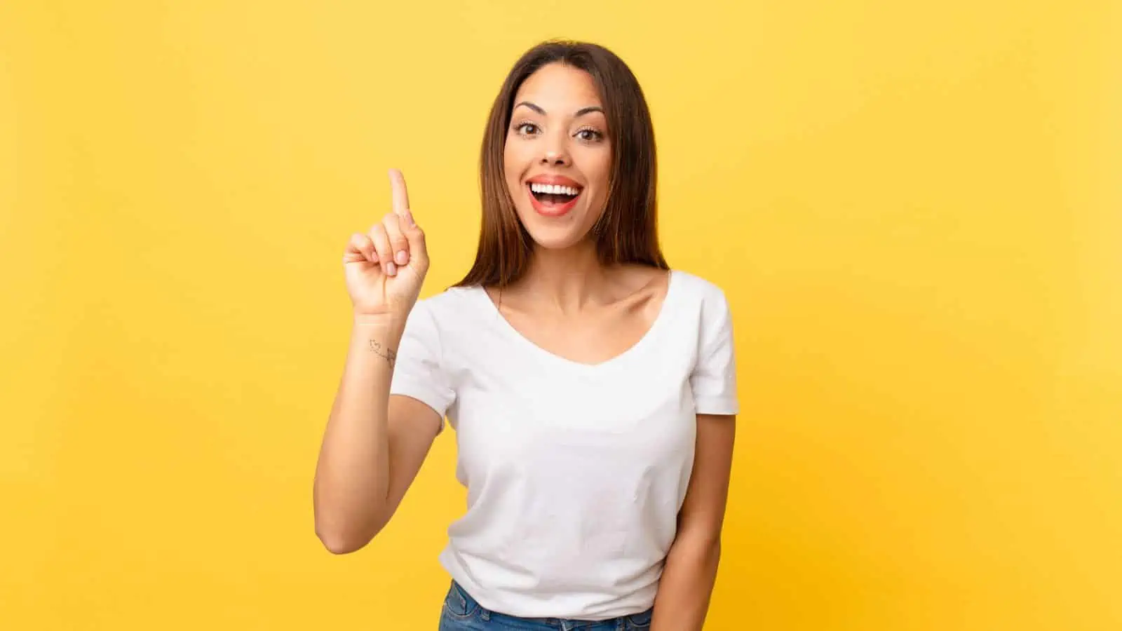 happy woman pointing up yellow background (1)