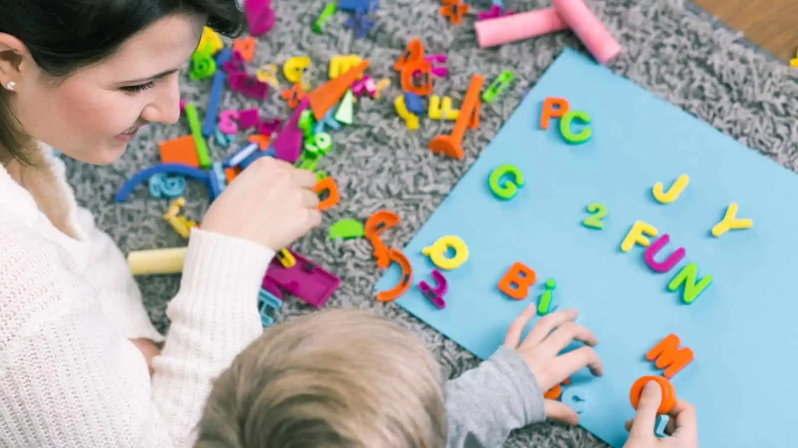 woman and child playing with magnetic alphabet letters