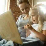 woman and child sitting on couch working on computer