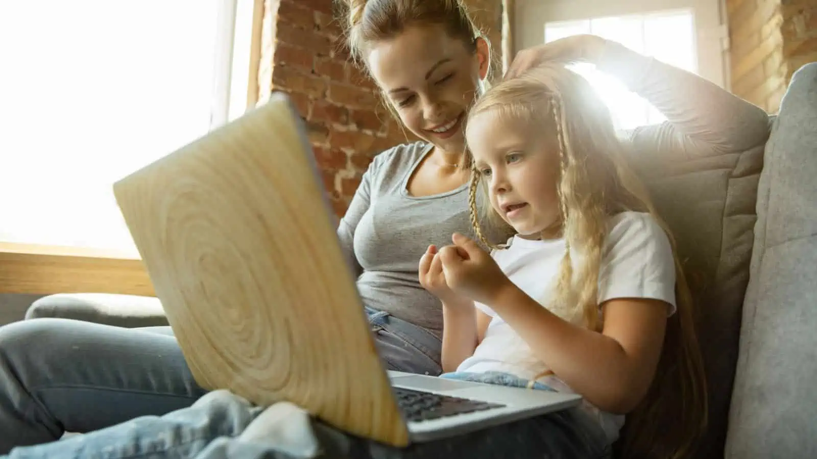 woman and child sitting on couch working on computer