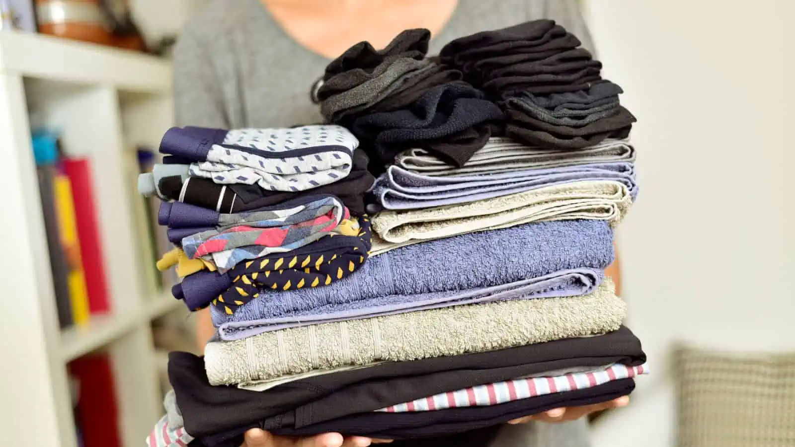 woman carrying a stack of folded clothes